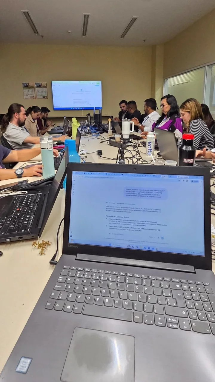 Profissionais participando de uma atividade prática com notebooks e fontes de apoio